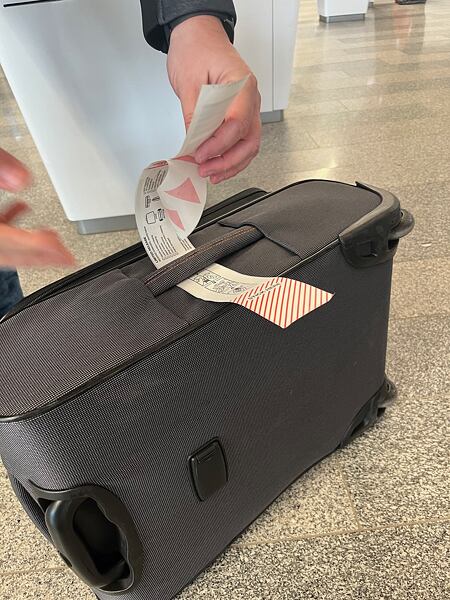 Štítek protáhněte uchem po delší straně kufru